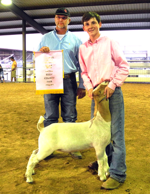 Kaylin Klein of Cottonwood 4-H shows his Reserve Champion meat goat as judge Jimmy Davis of Walter, Okla., holds his banner Wednesday evening at the Eddy County Fair. (Teresa Lemon - Daily Press)