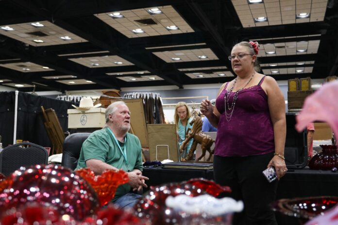 Patricia Roberts stands talking to Billy B. Mack about his collection of antique glass at his booth on Friday, Aug. 21 at the first annual Ruidoso Antique Show at the Ruidoso Convention Center. Mack is the owner of New Mexico Art Glass & Consulting in Ruidoso.